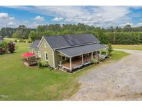 Charming home featuring solar panels, a welcoming front porch, and a spacious green lawn at 2646 Laurel Mill-Centerville Rd, Louisburg, NC 27549