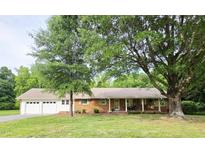 Charming brick ranch-style home with attached garage, mature trees and a well-manicured lawn at 3669 W Greensboro Chapel Hill Rd, Liberty, NC 27298