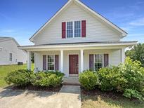 Charming home showcasing a covered front porch, attractive landscaping, and red shutters at 4025 Scofield Dr, Raleigh, NC 27610