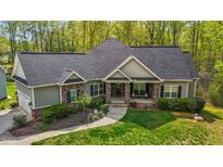 Charming home with stone accents, inviting front porch, beautiful landscaping, and a well-maintained lawn at 4036 Mackenzie Dr, Haw River, NC 27258