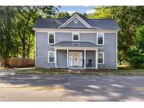 Charming two-story home featuring a metal roof and inviting front porch, surrounded by mature trees at 411 E Green St, Franklinton, NC 27525