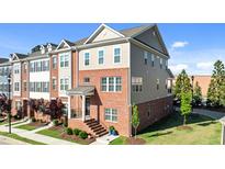 Stunning three-story townhome featuring a brick facade, welcoming entrance, and manicured landscaping at 518 Toran Dr, Wake Forest, NC 27587