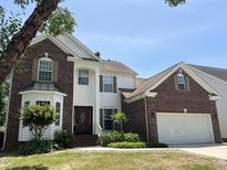 Charming brick and white home featuring a manicured lawn, two-car garage, and inviting front entrance at 5708 Big Sandy Dr, Raleigh, NC 27616