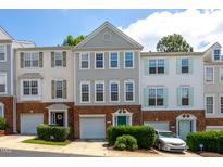 Charming townhome exterior featuring brick accents, a one-car garage, and colorful doors at 7244 Galon Glen Rd, Raleigh, NC 27613