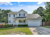 Charming two-story home with a well-manicured lawn, inviting porch, and attached two-car garage at 105 Tactical Dr, Bunnlevel, NC 28323
