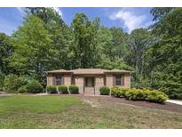 Charming brick ranch home with lush landscaping and mature trees on a sunny day at 136 Sycamore St, Cary, NC 27513