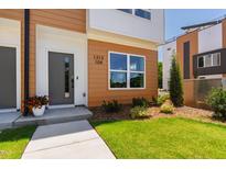 Modern townhouse exterior featuring a gray front door, wood facade, and manicured landscaping at 1408 Sawyer Rd # 103, Raleigh, NC 27610