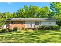 Charming single-story home featuring a brick and white facade with a well-maintained lawn and mature trees at 1593 Washington Ave, Creedmoor, NC 27522
