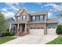 Charming two-story home featuring brick and siding, a covered porch, a two-car garage, and landscaped front yard at 1716 Longmont Dr, Wake Forest, NC 27587