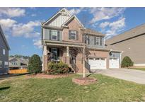 Charming two-story home with a brick and gray siding, a two car garage and a well manicured front lawn at 1716 Longmont Dr, Wake Forest, NC 27587