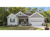 Charming single-story home featuring a well-manicured lawn, gray siding, and a two-car garage in a peaceful, wooded setting at 176 Lowery Ln, Benson, NC 27504