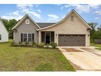 Charming single-story home featuring a mix of brick and vinyl siding, a two-car garage, and well-maintained landscaping at 1828 Wellspring Ct, Graham, NC 27253