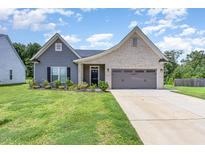 Charming home with a brick and gray siding, well-maintained lawn, and attached two-car garage at 1828 Wellspring Ct, Graham, NC 27253