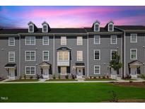 Charming townhomes feature well-manicured lawns and inviting entrances under a colorful sky at 2006 Nola Ln, Durham, NC 27713