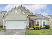 Charming home exterior featuring stone accents, manicured lawn, and an attached two-car garage at 2410 Kinglass Dr, Fuquay Varina, NC 27526