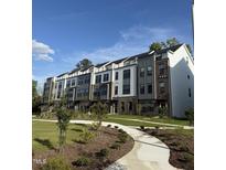 Beautiful townhome exterior with well-manicured lawn and sidewalk leading to the front entrances under a blue, partly cloudy sky at 3104 Kempthorne Rd # 48, Cary, NC 27519