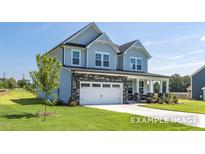 Charming two-story home featuring stone accents, a two-car garage, a welcoming front porch, and a well-manicured lawn at 444 Golden Dragonfly St, Wake Forest, NC 27587