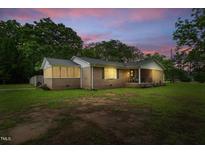 Charming brick ranch-style home featuring a screened porch and covered front porch, nestled on a spacious lot with mature trees at 5129 Neighbors Rd, Mebane, NC 27302