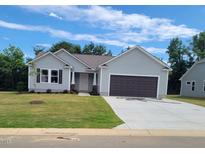 Charming single-Gathering home with a well-maintained lawn and attached two-car garage on a sunny day at 92 Oakfield Trace Dr, Four Oaks, NC 27524