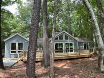 Charming home boasts a spacious wooden deck and is surrounded by lush greenery and trees at 102 Pebble Ct, Chapel Hill, NC 27516