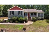 Charming home featuring a quaint front porch, landscaped yard, and tree-lined backdrop at 106 Nations Cove, Louisburg, NC 27549