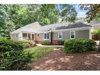 Charming home exterior with lush landscaping, a front porch, and neutral color palette nestled among mature trees at 108 Ripplewater Ln, Cary, NC 27518