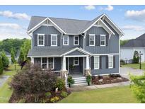 Charming two-story home with gray siding, landscaped yard, and a welcoming front porch at 109 Big Timber Path, Holly Springs, NC 27540
