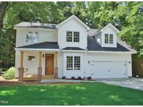 Charming two-story home featuring a covered porch, a two-car garage, and lush green lawn at 1104 Barrow Nook Ct, Apex, NC 27502