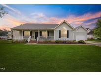 Charming single-story home featuring a welcoming front porch and a well-manicured lawn at 124 Roscommon Ln, Clayton, NC 27520