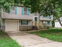 Charming home with teal shutters and a well-maintained front yard and attached one-car garage at 1509 Elkpark Dr, Raleigh, NC 27610