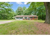Charming one-story home with a brick exterior, complemented by lush green lawn and mature trees at 211 Cool Spring Rd, Durham, NC 27713