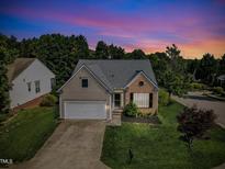 Charming home featuring a well-maintained yard, attached garage, and classic architectural details under a vibrant sunset at 3400 Secretariat Way, Raleigh, NC 27614
