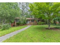 Charming brick home with a walkway, mature trees, and a well-manicured lawn at 4030 King Charles Rd, Durham, NC 27707