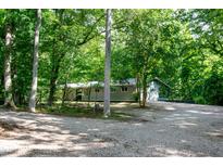 Secluded single-story home featuring mature trees and a gravel driveway at 5213 Tomahawk Trl, Raleigh, NC 27610