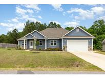 Charming home with blue siding, stone accents, a well-manicured lawn, and attached garage at 565 Joseph Alexander Dr, Fuquay Varina, NC 27526