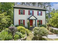 Charming two-story home with red shutters, landscaped yard, and forest backdrop at 5704 Cholderton Ct, Raleigh, NC 27604