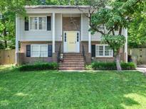 Charming two-story home with brick accents, a welcoming yellow door, and a well-manicured lawn at 7605 Copper Mine Ln, Raleigh, NC 27615
