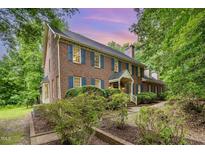 Charming two-story brick home with blue shutters surrounded by lush greenery at 7801 Wood Way Ct, Raleigh, NC 27606