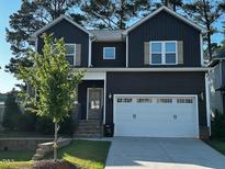Charming two-story home with a modern dark exterior, a two-car garage, and a well-maintained front yard at 809 Trinity Park Dr, Wake Forest, NC 27587