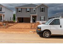 Unfinished two-story home featuring gray siding, an attached two-car garage, and professional equipment at the front at 1138 Winding Spring Dr, Mebane, NC 27302