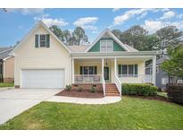 Charming yellow two-story home with a welcoming front porch and attached two car garage at 1208 Dunn Creek Xing, Wake Forest, NC 27587