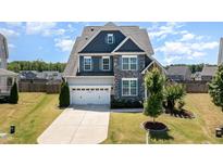 Inviting two-story home with blue and gray facade, manicured lawn, and a spacious driveway leading to a two-car garage at 123 Gunderson Ln, Garner, NC 27529