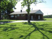 Charming brick ranch-style home featuring a well-maintained lawn and a covered carport area at 1700 Warrenton Rd, Henderson, NC 27537