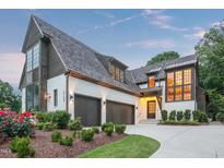 Beautiful two-story home featuring a manicured lawn, three-car garage, and brick and wood exterior at 2120 Kipawa St, Raleigh, NC 27607