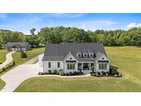 Stunning aerial view of a modern farmhouse featuring a black roof and lush green lawn at 2408 Eddie Howard Rd, Willow Springs, NC 27592