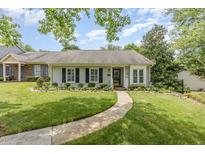 Charming single-story home featuring manicured lawn, flower beds, and a curved walkway leading to the front door at 2617 Cottage Cir, Raleigh, NC 27613