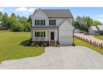 Charming two-story home with a welcoming front porch, gravel drive, and lush green lawn at 412 Carr Store Rd, Cedar Grove, NC 27231