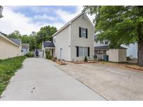 Traditional two-story home with light beige siding and a long driveway, complemented by lush green trees at 505 Stratton Way, Durham, NC 27704