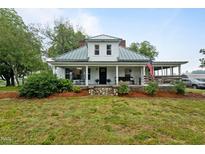 Charming two-story farmhouse featuring a covered front porch, metal roof, and well-maintained lawn at 6447 Beulah Church Rd, Liberty, NC 27298