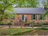 Charming brick home featuring a beautifully landscaped front yard and a vibrant teal front door at 6925 Valley Lake Dr, Raleigh, NC 27612